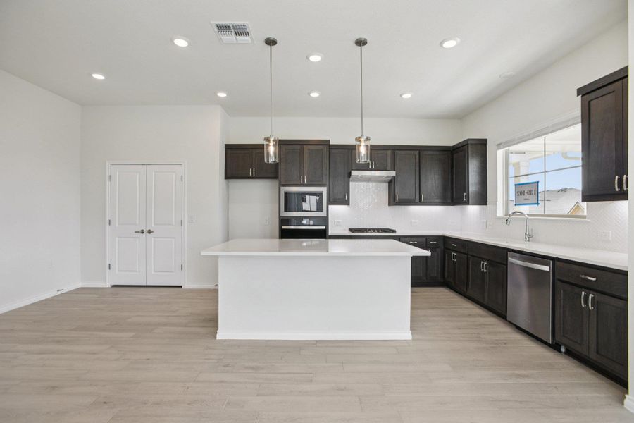 Kitchen with a kitchen island, decorative light fixtures, decorative backsplash, recessed lighting, and stainless steel appliances