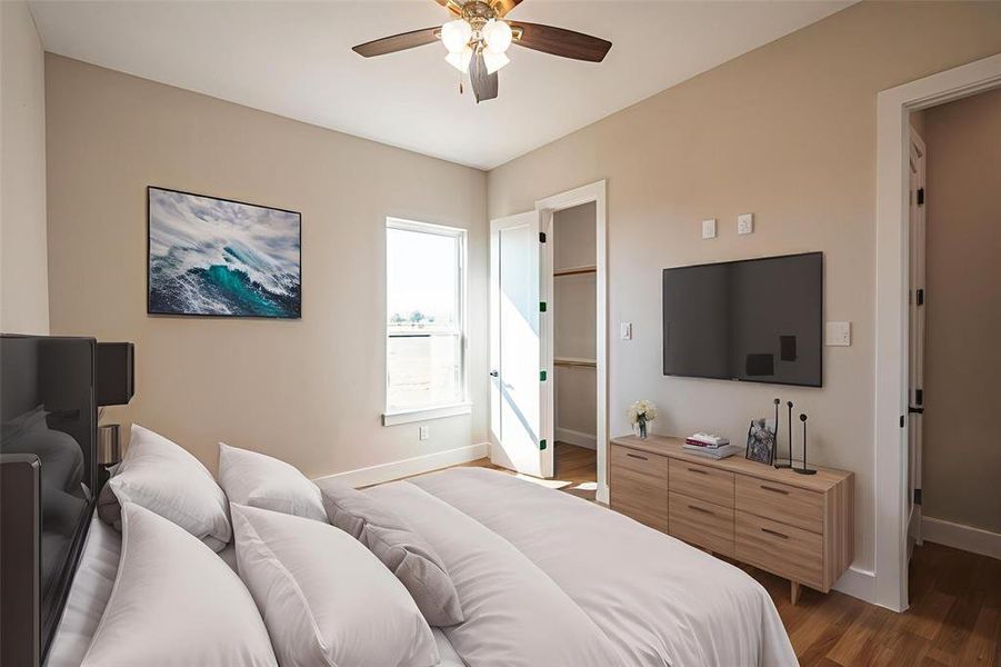 Bedroom featuring dark wood finished floors, a spacious closet, and ceiling fan