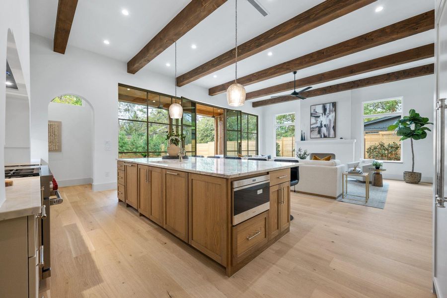 Kitchen featuring pendant lighting, brown cabinetry, healthy amount of natural light, light stone countertops, and recessed lighting Kitchen featuring pendant lighting, brown cabinetry, healthy amount of natural light, light stone countertops, and recessed lighting