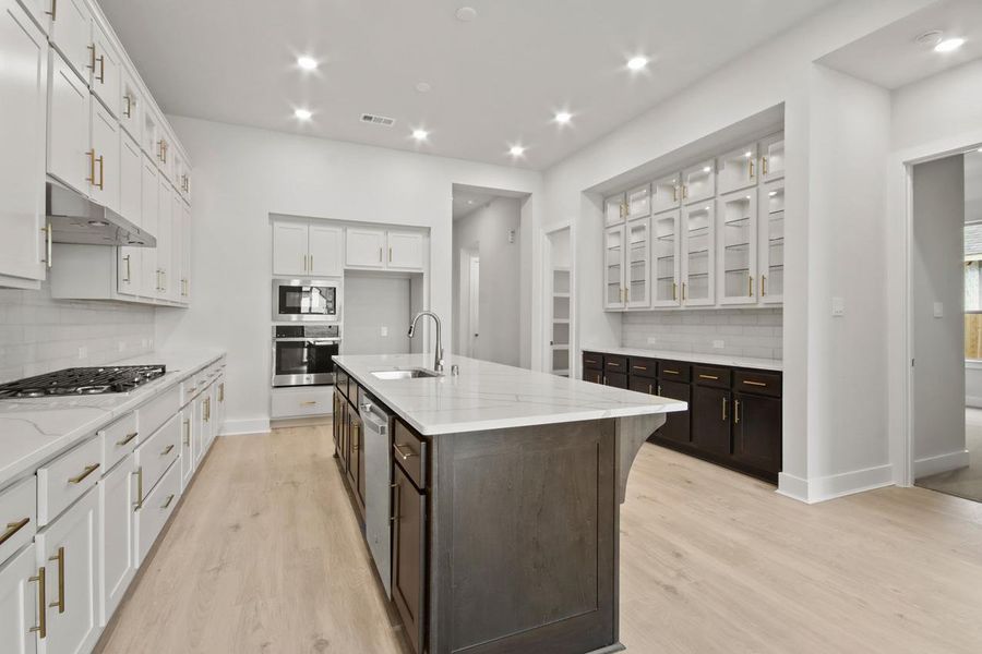 Kitchen featuring under cabinet range hood, a sink, light wood-style floors, and appliances with stainless steel finishes Kitchen featuring under cabinet range hood, a sink, light wood-style floors, and appliances with stainless steel finishes