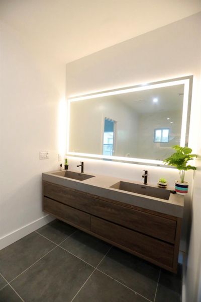 Full bath with double vanity and dark tile patterned floors