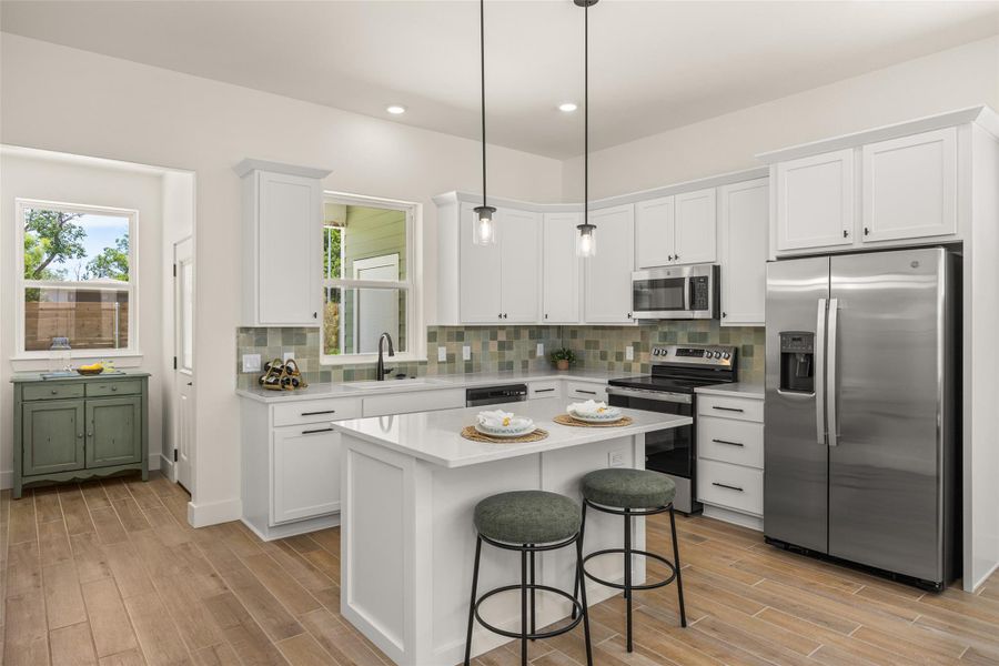 A pristine white kitchen features a central island, stainless steel appliances, and wood-look tile flooring.