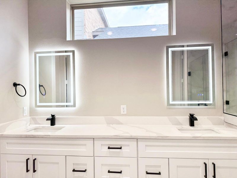 Luxurious primary bathroom featuring a modern double vanity with sleek fixtures and LED-lit mirrors, offering both style and functionality.