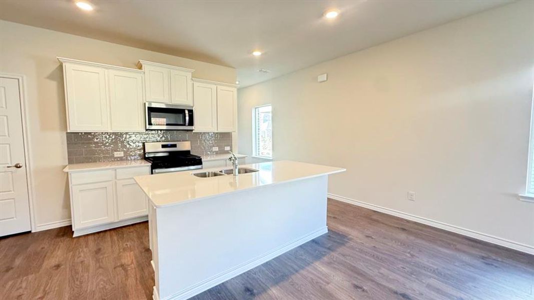 Kitchen featuring white cabinets, backsplash, stainless steel appliances, dark wood finished floors, and recessed lighting Kitchen featuring white cabinets, backsplash, stainless steel appliances, dark wood finished floors, and recessed lighting