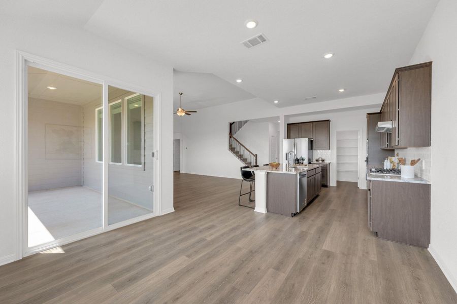 Kitchen featuring a breakfast bar, ceiling fan, recessed lighting, a kitchen island with sink, and light wood finished floors Kitchen featuring a breakfast bar, ceiling fan, recessed lighting, a kitchen island with sink, and light wood finished floors