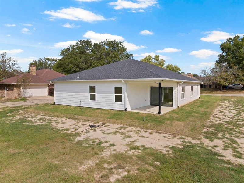 Rear view of property with a yard, a patio, and a shingled roof