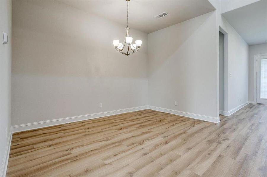 Empty room featuring a notable chandelier and light wood-type flooring