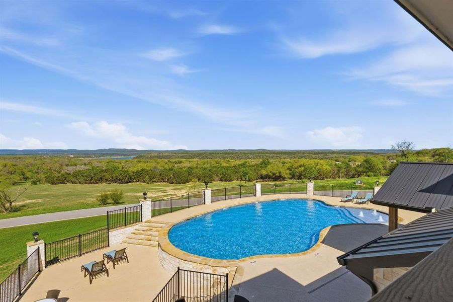 An inviting in-ground pool offers sweeping, verdant landscape views under a vast sky.