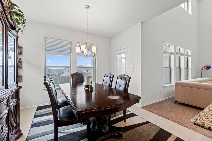 Bright dining area featuring a contemporary chandelier, multiple windows with natural light, and light-toned flooring