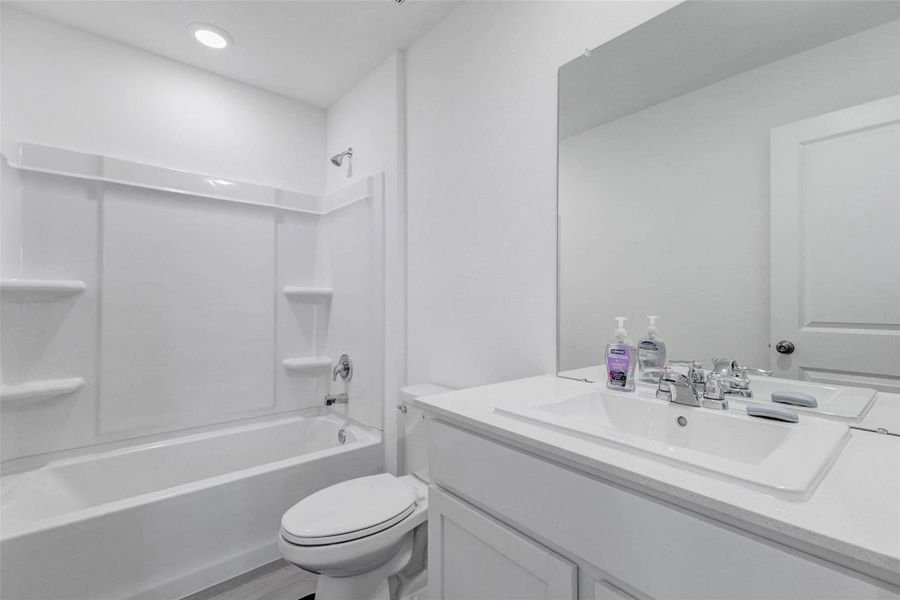 Full secondary bathroom featuring a tub/shower combination, vanity with storage, and modern finishes.
