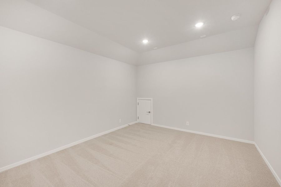 Empty room with white walls, beige carpet, recessed lighting, and a single door Empty room with white walls, beige carpet, recessed lighting, and a single door