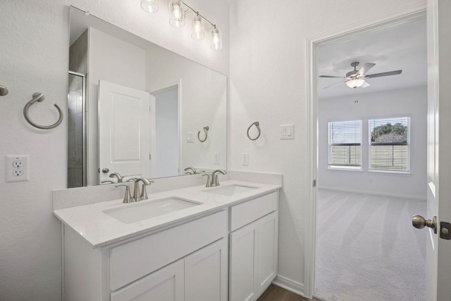 Full bath with double vanity, a ceiling fan, a shower stall, and dark carpet