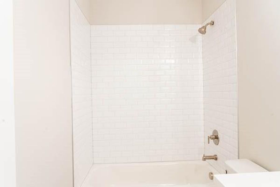 Bathroom with tiled shower / bath combo and toilet Bathroom with tiled shower / bath combo and toilet