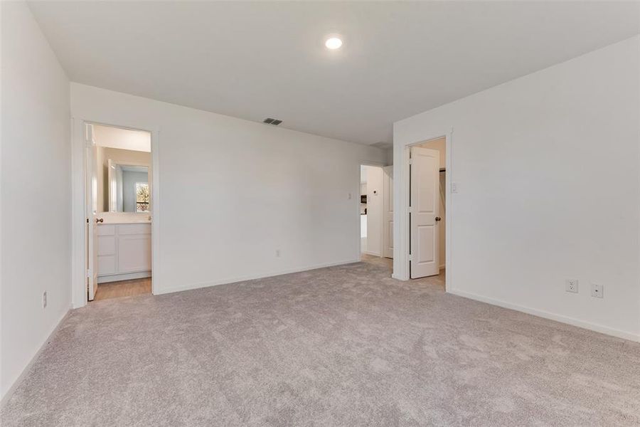 Unfurnished bedroom with ensuite bath and light colored carpet