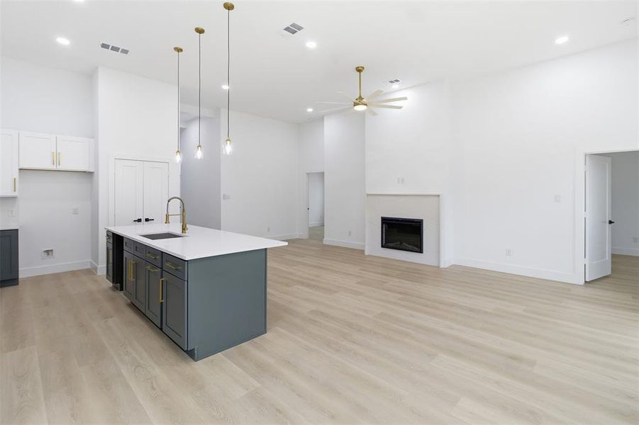 Kitchen with a high ceiling, gray cabinetry, open floor plan, white cabinetry, and decorative light fixtures