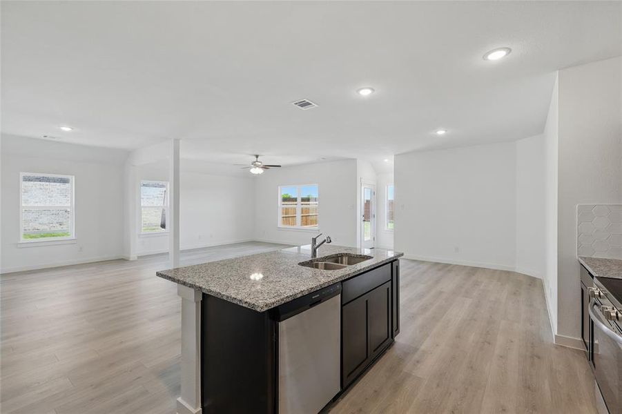 Kitchen with visible vents, a sink, open floor plan, light wood finished floors, and stainless steel appliances Kitchen with visible vents, a sink, open floor plan, light wood finished floors, and stainless steel appliances