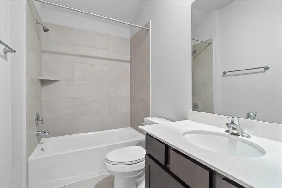 A streamlined secondary bathroom providing a functional tub/shower combination, vanity with modern fixtures seamlessly blending practicality and style.