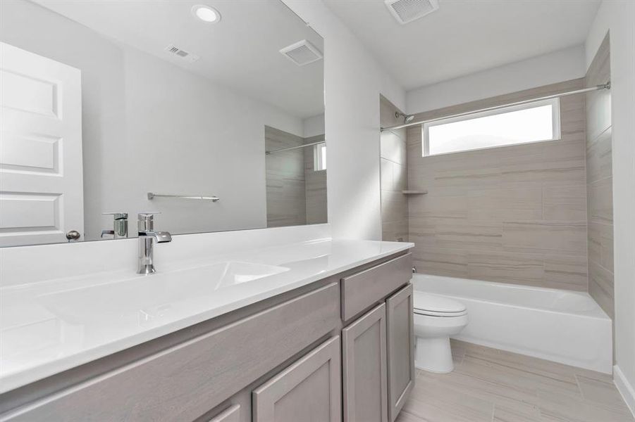 Experience sophistication in the secondary bathroom, where tile flooring complements a bath/shower combo with tile surround. Light wood cabinets complete with a beautiful light countertop, enhances the space for a truly inviting ambiance. Sample photo of completed home with similar floor plan. As-built interior colors and selections may vary.