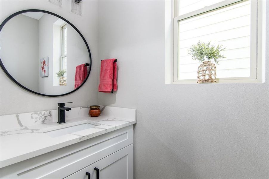 Half bath off of entry way with calacatta quartz counter top.