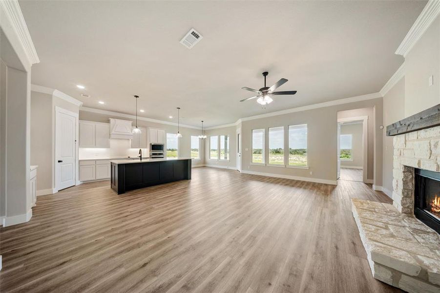 Unfurnished living room with a fireplace, a ceiling fan, ornamental molding, light wood finished floors, and recessed lighting Unfurnished living room with a fireplace, a ceiling fan, ornamental molding, light wood finished floors, and recessed lighting