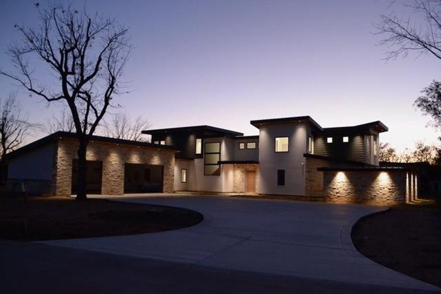 View of front of home with curved driveway, stucco siding, stone siding, and a garage View of front of home with curved driveway, stucco siding, stone siding, and a garage