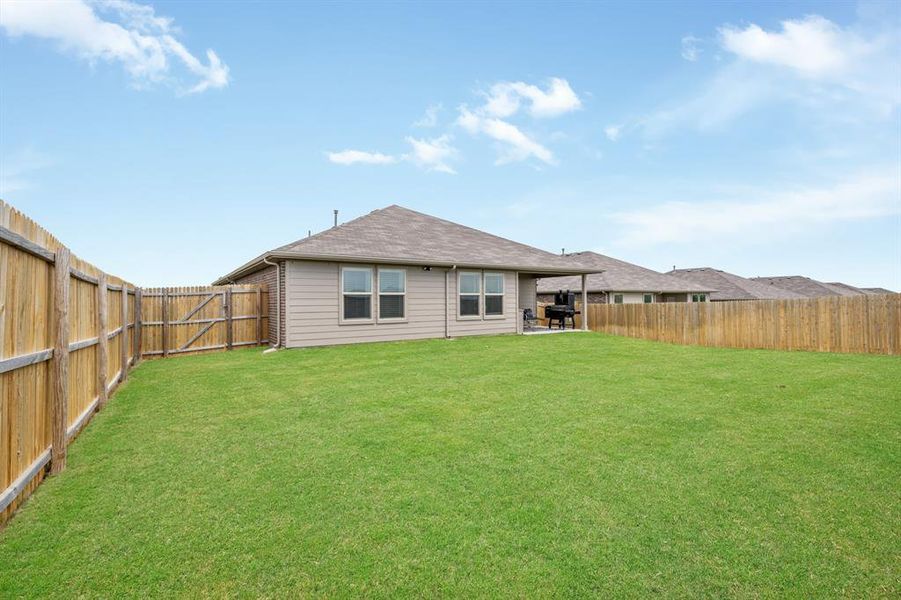 Rear view of property featuring a patio, a fenced backyard, and roof with shingles