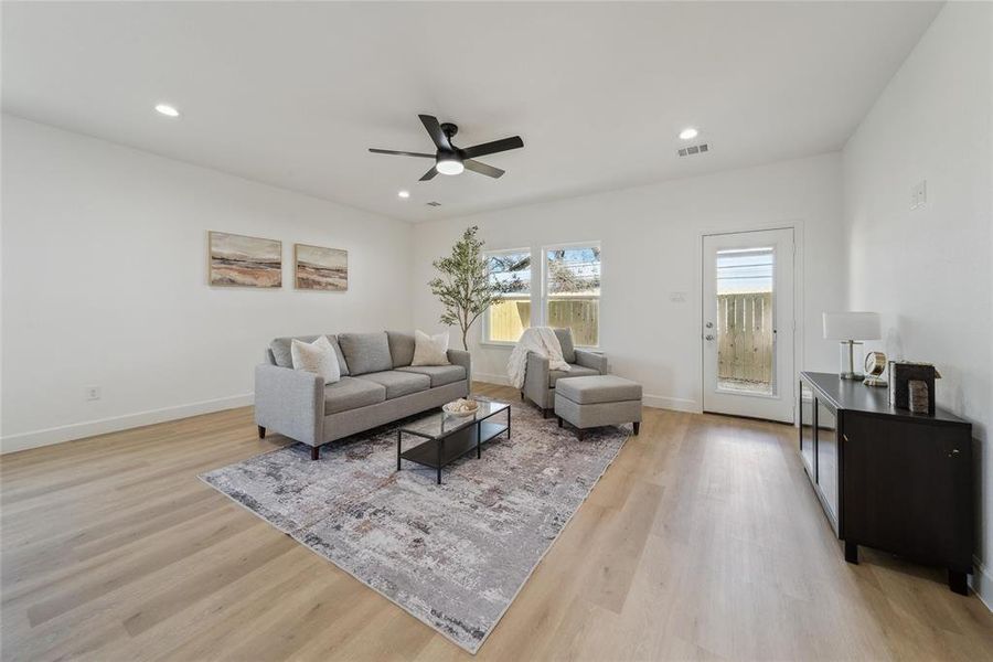 Living room with ceiling fan and light hardwood / wood-style flooring