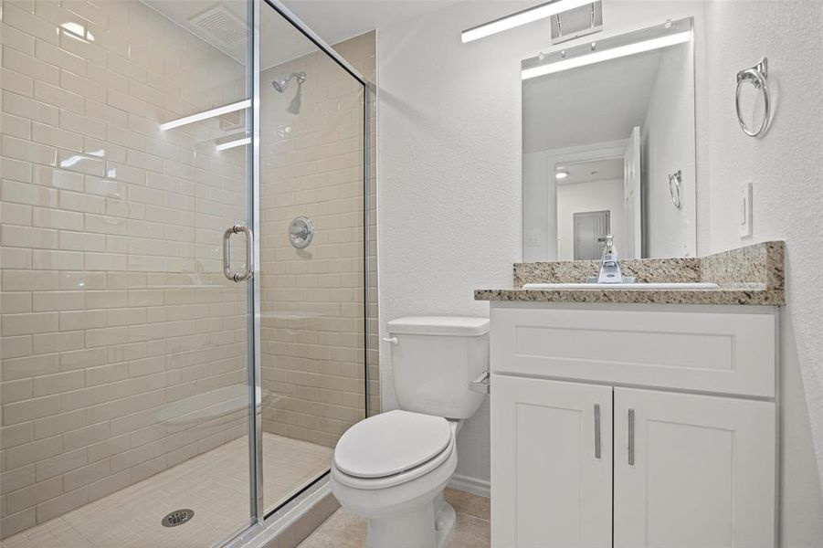 Bathroom with tile patterned floors, vanity, toilet, and walk in shower