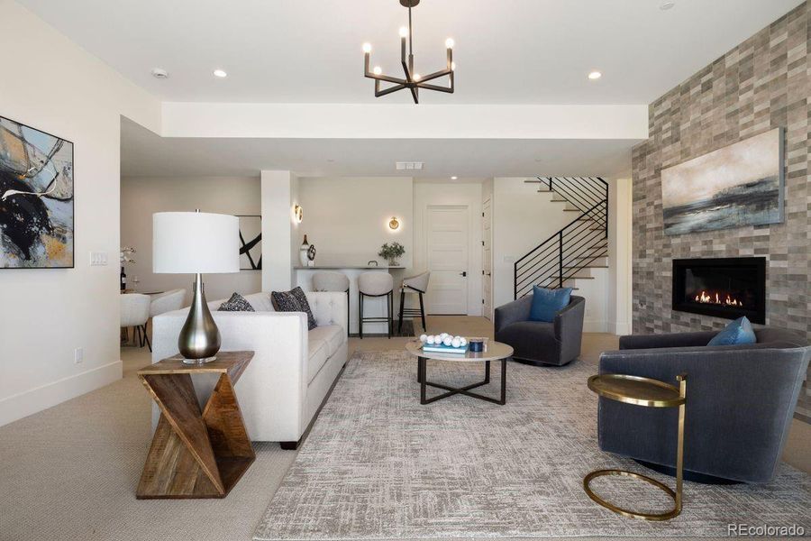 Sophisticated lower-level family room with sleek modern finishes, a statement fireplace, and a chic wet bar designed for effortless entertaining.