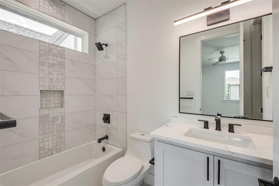 Full bathroom featuring ceiling fan, vanity, toilet, and tiled shower / bath