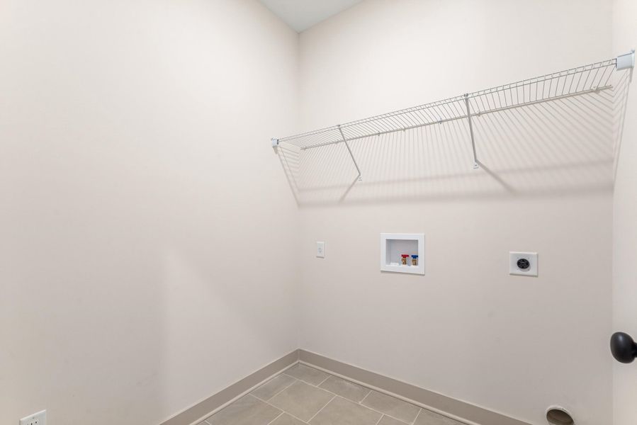 Laundry room with electric dryer hookup, hookup for a washing machine, and light tile patterned flooring
