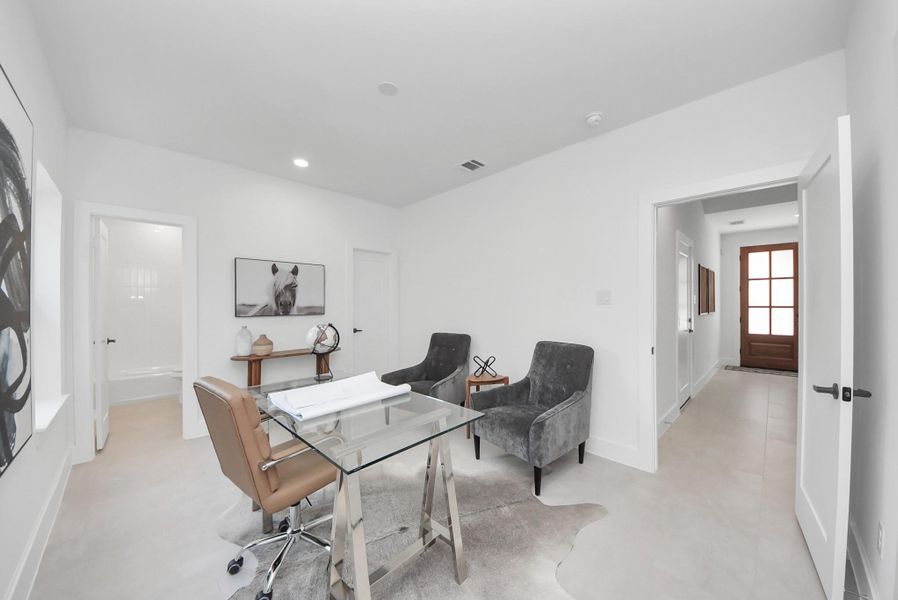This bright home office is designed for both style and productivity. A glass desk with a brown leather chair is paired with two gray upholstered chairs, while light walls and recessed lighting enhance the airy feel. Decorative accents on a side table add warmth, and the adjoining hallway leads seamlessly to other areas of the home. This bright home office is designed for both style and productivity. A glass desk with a brown leather chair is paired with two gray upholstered chairs, while light walls and recessed lighting enhance the airy feel. Decorative accents on a side table add warmth, and the adjoining hallway leads seamlessly to other areas of the home.