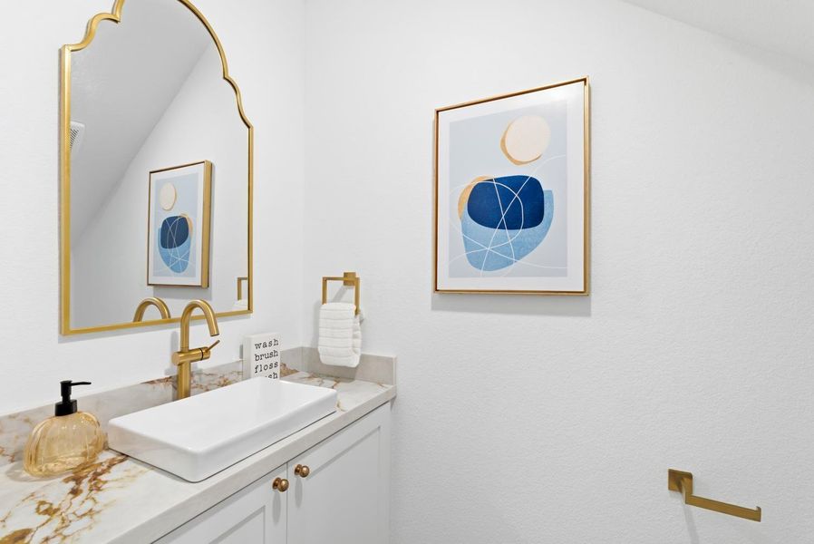 Tucked underneath the stairs is a chic half-bath featuring hexagon tile flooring, a modern floating vanity, and a decorative mirror, offering a sophisticated and functional touch for guests.