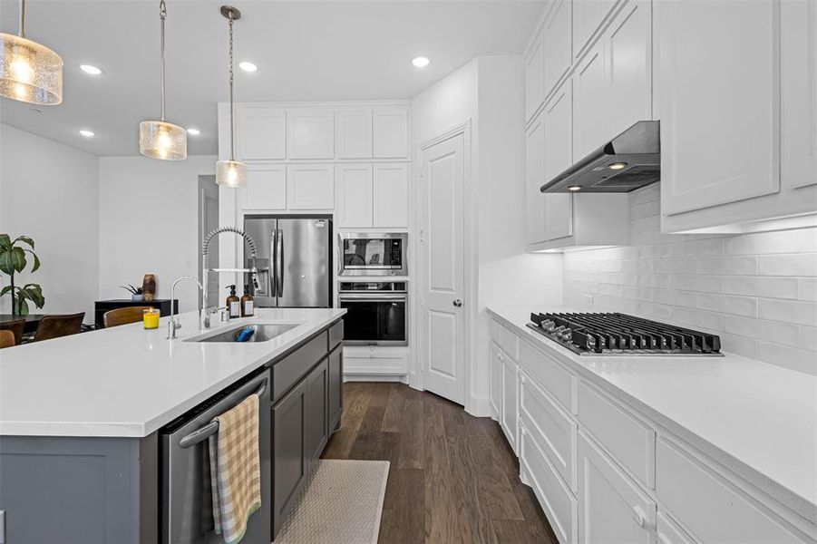 Kitchen with white cabinetry, dark wood finished floors, decorative light fixtures, stainless steel appliances, and recessed lighting