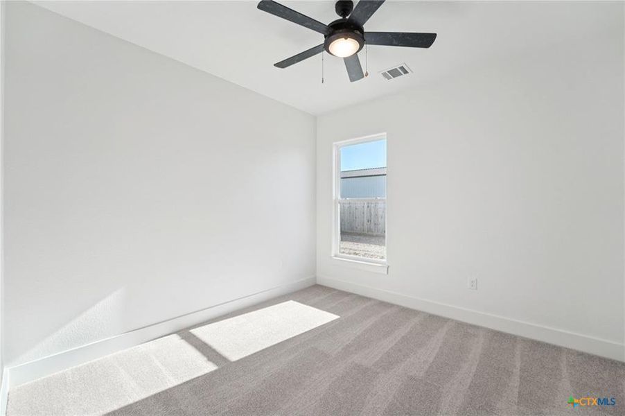 A well-lit bedroom features plush carpet flooring and a modern ceiling fan for ultimate comfort. A well-lit bedroom features plush carpet flooring and a modern ceiling fan for ultimate comfort.