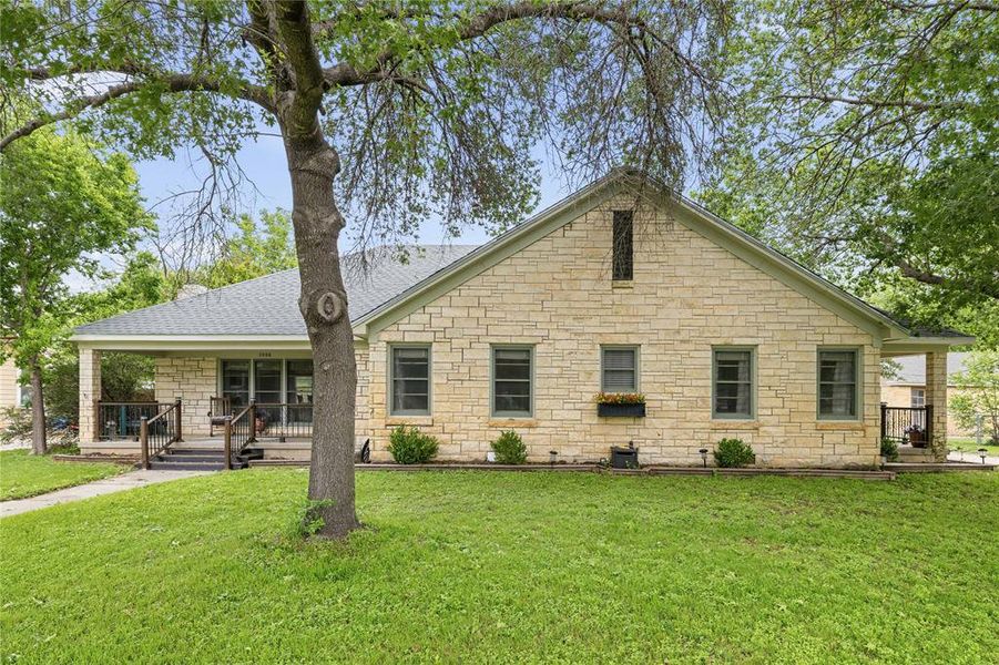 Stone exterior featuring a covered front porch, gabled roofline, multiple windows, and a window box Stone exterior featuring a covered front porch, gabled roofline, multiple windows, and a window box