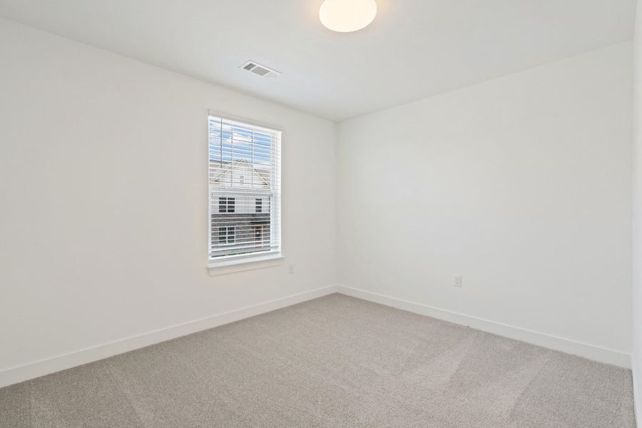 Bright interior space featuring light gray carpet, white walls, and a window with blinds
