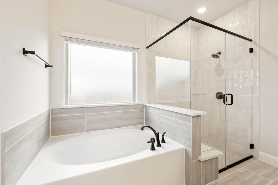 Master bathroom with soaking tub, glass-enclosed walk-in shower, gray tile, and black fixtures