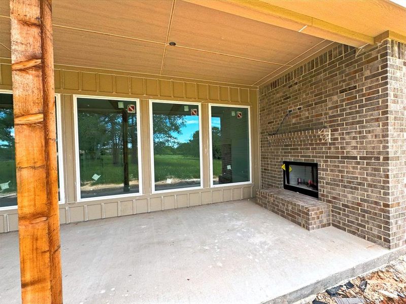 View of patio with an outdoor brick fireplace