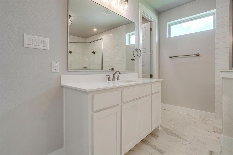 Bathroom with tile patterned flooring, vanity, and a tile shower