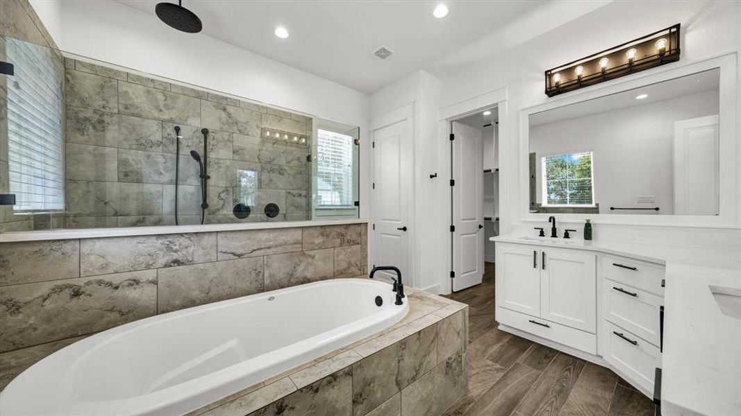 Bathroom featuring hardwood / wood-style flooring, plus walk in shower, and vanity