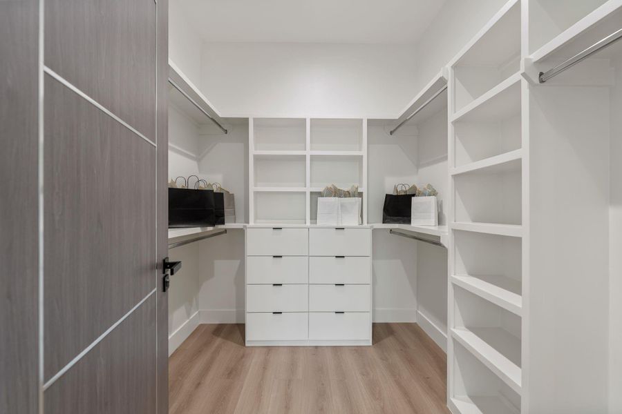 The walk-in closet features a custom built-in storage solution with perimeter shelving and hanging rods on multiple walls — a fully dedicated, well-organized storage space that lives up to the scale of the suite it serves.