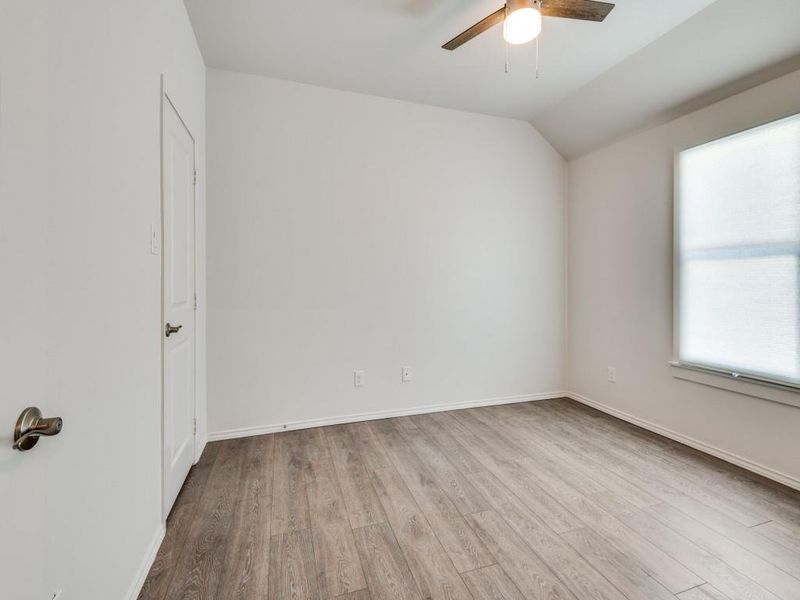 Empty room featuring ceiling fan, lofted ceiling, and hardwood / wood-style floors