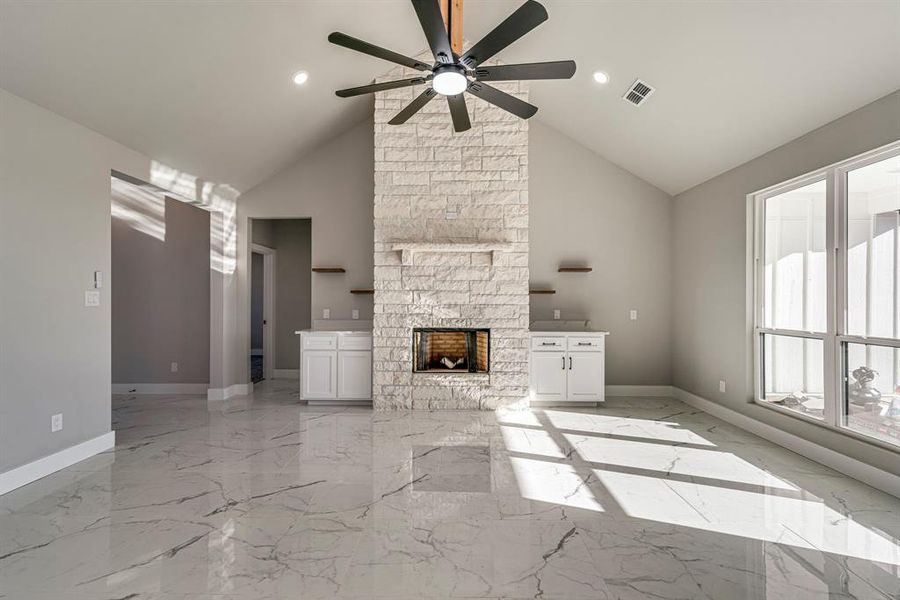 Unfurnished living room featuring marble finish floor, a fireplace, baseboards, and a ceiling fan