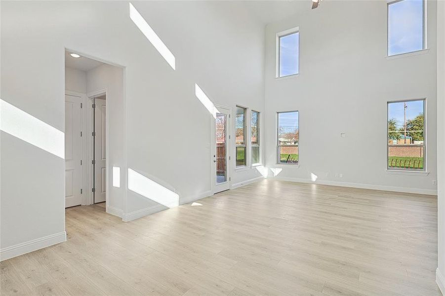 Unfurnished living room with light wood-type flooring and a high ceiling