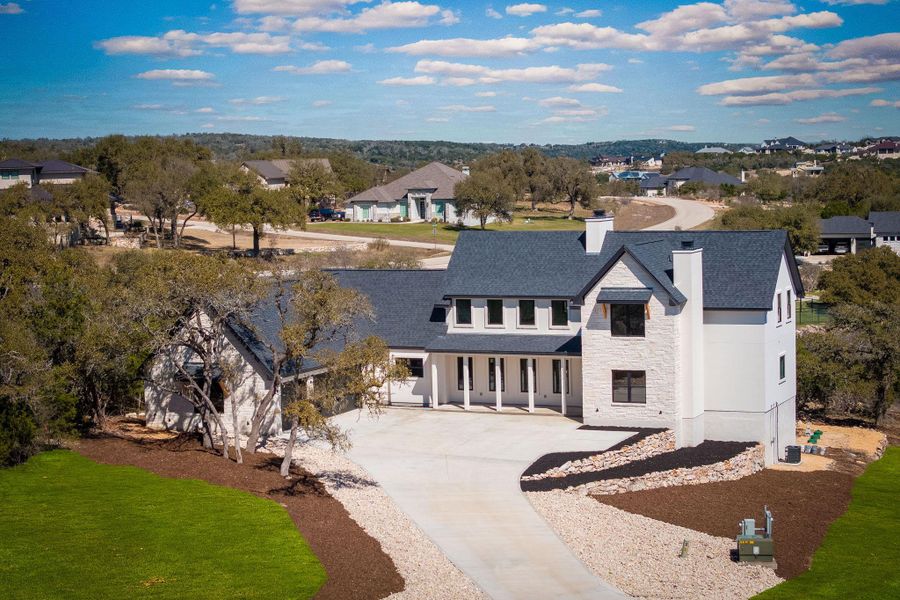 Modern farmhouse with stone siding, concrete driveway, a residential view, stucco siding, and a chimney