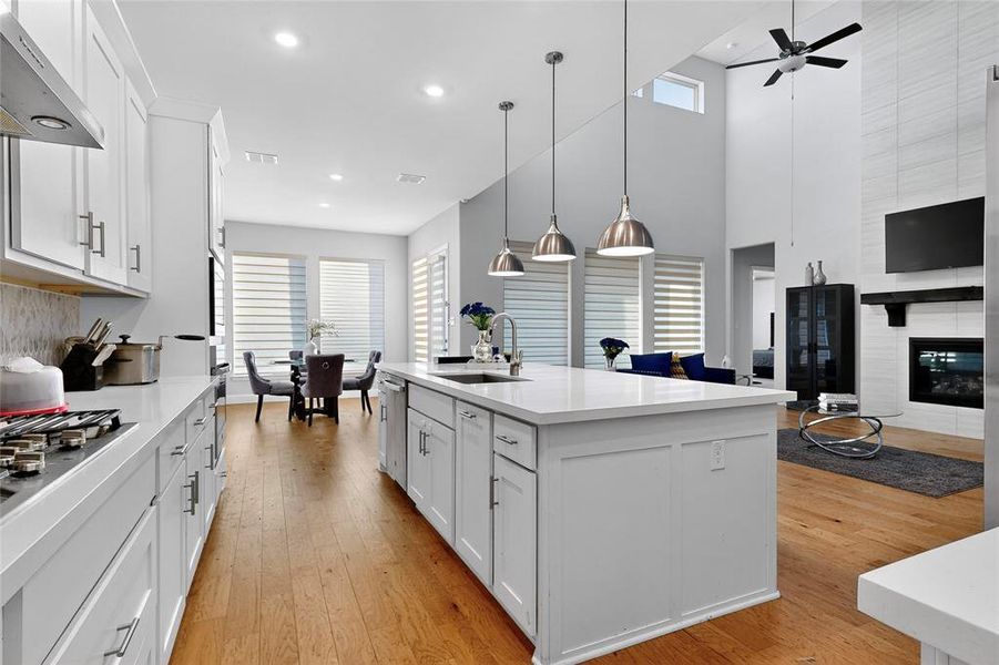 Kitchen featuring white cabinets, a ceiling fan, range hood, light wood-type flooring, and recessed lighting