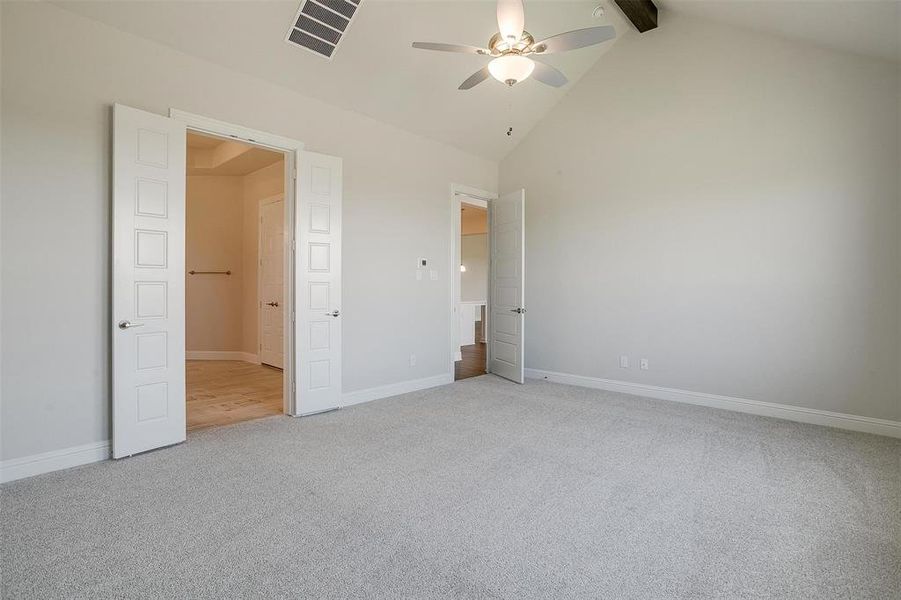 Unfurnished bedroom with high vaulted ceiling, carpet, ceiling fan, and beamed ceiling