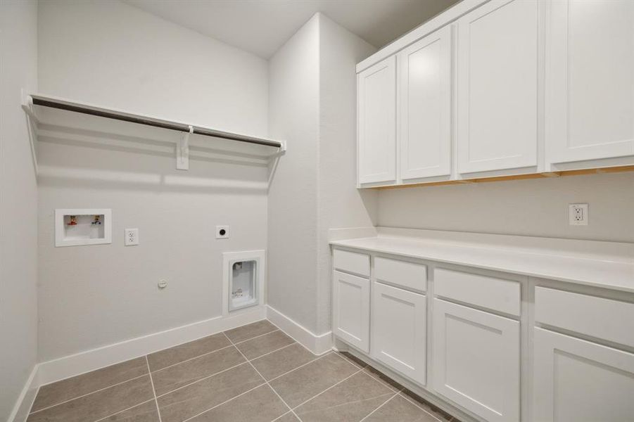 Washroom featuring cabinets, hookup for a washing machine, gas dryer hookup, electric dryer hookup, and light tile patterned floors