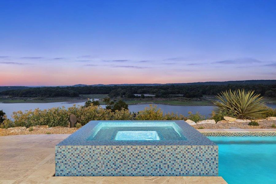 Outdoor pool area featuring an integrated, tiled spa with a vibrant blue interior